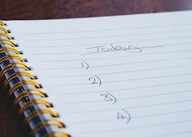 A close-up view of a handwritten to-do list on a spiral notebook with numbers for tasks.
